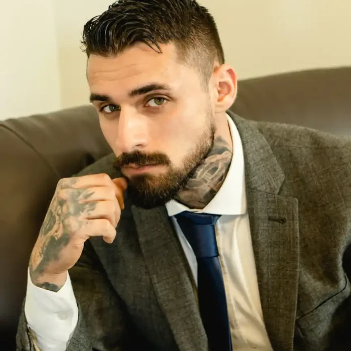 portrait of a man with tattoos wearing a gray suit